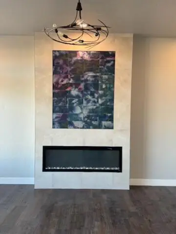 Modern living room featuring a stylish fireplace with glass stones, a large abstract artwork above, and a contemporary chandelier Modern living room featuring a stylish fireplace with glass stones, a large abstract artwork above, and a contemporary chandelier